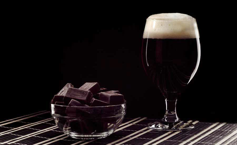 Cerveja com chocolate: uma combinação perfeita. Na imagem, pedaços de chocolate ao lado de uma taça de cerveja preta
