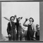 Cervejas feitas para o trabalhador: foto preto e branca antiga com três fazendeiros bebem suas cervejas no campo a frente de uma máquina colheitadeira antiga