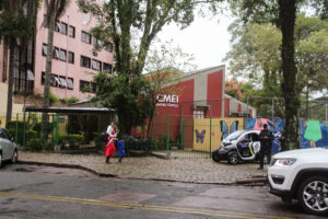criança e mãe brancas em frente a escola