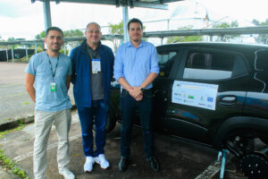 três homens brancos em frente a um carro